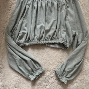 Grön blus med långa ärmar - Grön blus med långa ärmar och elastiska kanter. Tillverkad i ett mjukt material med 95% polyester och 5% elastan.