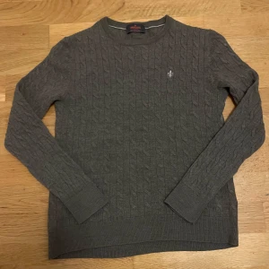 Morris stickad tröja - Säljer en stilren grå kabelstickad tröja från Morris i 100% merinoull. Tröjan har en broderad logga på bröstet. Den är i jättebra skick!😊