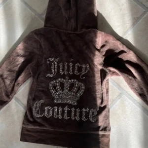 Brun hoodie med Juicy Couture tryck - Säljer en jättesöt brun hoodie med en stor krona och text i glittriga stenar på ryggen. Säljer då den inte kommer till användning <3