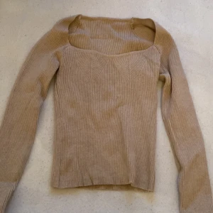 Beige ribbad tröja - Säljer en stilren beige ribbad tröja med lång ärm och fyrkantig halsringning. Perfekt för en enkel och snygg look. Passar bra till både jeans och kjol.