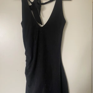 Svart glittrig klänning - Jätte fin svart halterneck klänning med glittrande detaljer och öppen rygg !!figur syd på ena sidan,Aldrig använd då den va för stor vid köpet.💕🙌