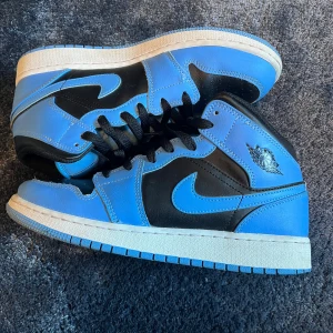 Nike Air Jordans i blått och svart - Snygga Nike Air Jordans i en fräsch kombination av blått och svart. Skorna har en klassisk design med snörning och den ikoniska Air Jordan-loggan på sidan. Perfekta för dig som vill ha stil och komfort i ett. Man kan diskutera priset