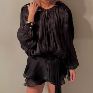 Svart klänning  med knytband - Elegant svart trendig klänning, lite skimmrig i färgen. 100% viscose Tillvörande minishorts att ha under klänningen. I nyskick, aldrig använd (med prislapp). Nypris - 1700