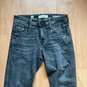 Replay jeans - Helt nya Snygga grå jeansbyxor från Replay i modellen Anbass. De har en slim fit passform och är tillverkade av ekologisk bomull. Byxorna har klassisk femficksdesign och knappar i midjan.