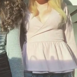 Ljusrosa ribbad omlottopp - Säljer en söt ljusrosa ribbad omlottopp med volangdetalj. Toppen har långa ärmar och en v-ringad design. Köpte från Nelly 