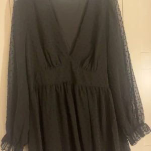 Svart kortklänning med prickigt mönster - Supersöt svart långärmad klänning. Djup v-ringning och lätt volang i kjolen ger en romantisk vibe. Helt oanvänd, endast testad 🌸