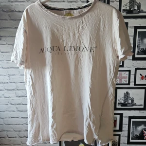 Acqua Limone t-shirt med tryck - Snygg urtvättad t-shirt från Acqua Limone med klassiskt tryck framtill och stor gul citron på ryggen. T-shirten har rund hals, korta ärmar och är gjord i mjuk bomull. Perfekt för en chill och avslappnad stil.