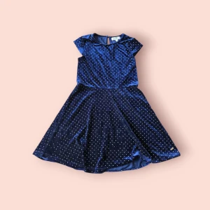 Mörkblå sammetsklänning Hampton Republic - Supersöt mörkblå sammetsklänning från Hampton Republic med korta ärmar och guldiga prickar över hela tyget. Klänningen har en klassisk rund halsringning och ett lätt utställt kjolparti som ger en fin siluett. Perfekt för dig som vill sticka ut lite extra!