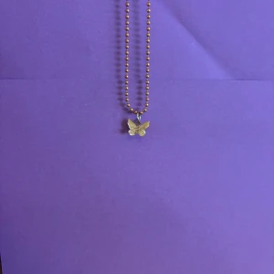 Guldigt halsband med fjärilshänge - Snyggt halsband med kulkedja i guldton och ett detaljrikt fjärilshänge. Perfekt accessoar för dig som gillar söta och trendiga smycken med en touch av naturinspiration.