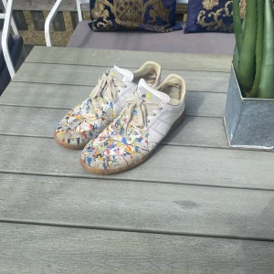 Maison Margiela sneakers med färgstänk - Säljer dessa Maison Margiela sneakers med färg på, storlek 46, rätt använda men har mycket kvar i dom! Online kvitto finns om behövs, inget följer med