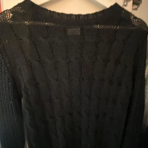 Svart kabelstickad tröja - Svart kabelstickad tröja med grovt mönster och rund hals. Perfekt för kyliga dagar och enkel att matcha med olika outfits. Långärmad och i mjukt stickat material som ger en avslappnad och snygg look.