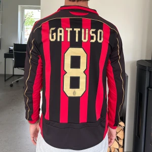 AC Milan Gattuso långärmad matchtröja - Säljer en klassisk AC Milan långärmad fotbollströja från Adidas med Gattuso och nummer 8 på ryggen. Tröjan har röda och svarta vertikala ränder, guldiga detaljer och klubbmärke på bröstet. Champions League-märke på ärmen och Bwin som sponsor framtill.