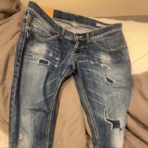 dondup george - Snygga blå jeans med slitningar och hål på benen för en trendig, avslappnad look. Klassisk femficksmodell med låg midja och smal passform. Perfekta för dig som gillar en edgy streetstyle.