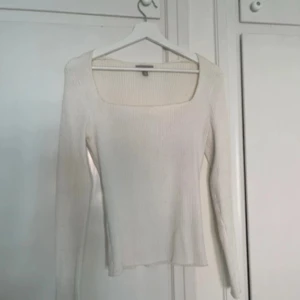 Vit ribbad långärmad tröja H&M - Säljer en vit ribbad långärmad tröja från H&M i storlek S. Tröjan har en snygg fyrkantig urringning och är figurnära i modellen. Perfekt att styla med jeans eller kjol för en clean och fräsch look.