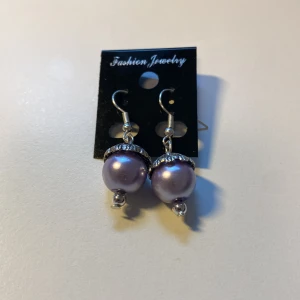 Unika, Handgjorda Lila pärlörhängen med silverdetaljer *Endast 1 Kvar* - Snygga örhängen med stora lila pärlor och coola silverfärgade detaljer upptill och nedtill. Hängande modell med krok, perfekta för att ge din look lite extra bling. Passar dig som gillar statement-smycken och vill sticka ut.