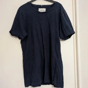 Mörkblå t-shirt från Ljung, stl S - Enkel och stilren mörkblå t-shirt från Ljung by Marcus Larsson i storlek S. T-shirten har rund halsringning och korta ärmar. Tillverkad i mjuk bomull som känns skön mot huden. Perfekt för en clean och avslappnad look. Lite ytnoppor förekommer, men är i väldigt bra skick. 