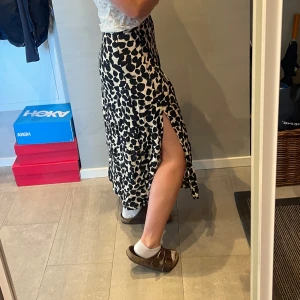 Svartvit leopardmönstrad långkjol - Säljer en svartvit långkjol med trendigt leopardmönster och  slits på båda sidor. Kjolen har en snygg, rak passform. Materialet känns lätt och flowy, vilket gör den superbekväm. 