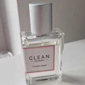 Clean Classic Flower Fresh parfym 30 ml - Clean Classic Flower Fresh är en fräsch parfym med tydliga inslag av citrus, vita blommor och en lätt blommig doft. Flaskan är genomskinlig och fyrkantig med en stilren silverfärgad kork och vit etikett med rosa ram. Perfekt för dig som gillar lätta och fräscha dofter.