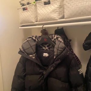 Svart pufferjacka från Burberry M - PRIS KAN DISKUTERAS MEN SKA VA EN SNABB SMIDIG AFFÄR Säljer en svart pufferjacka från Burberry med klassiskt rutigt foder i grått och vitt. Jackan har dragkedja och knappar framtill, hög krage och vadderad design som håller dig varm. Perfekt för kalla dagar och riktigt snygg streetstil.kan även bli till en väst men hjälp av dragkedjor som sitter på insidan av jackan 