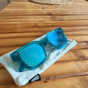 Chimi solglasögon 04 - Snygga solglasögon från Chimi i modellen #004, med blå båge och matchande blåtonade glas. Rektangulär form och cool, modern vibe. Perfekta för att sticka ut i sommar! Kommer endast med orginalpåsen. Repor finns!