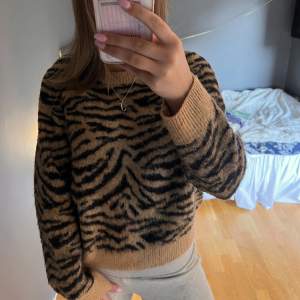 Säljer en mysig brun tröja med svart zebramönster. 