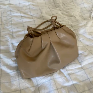 Beige väska  - Beige väska. Dumplingbag eller clutch. Ett litet fack inuti. 