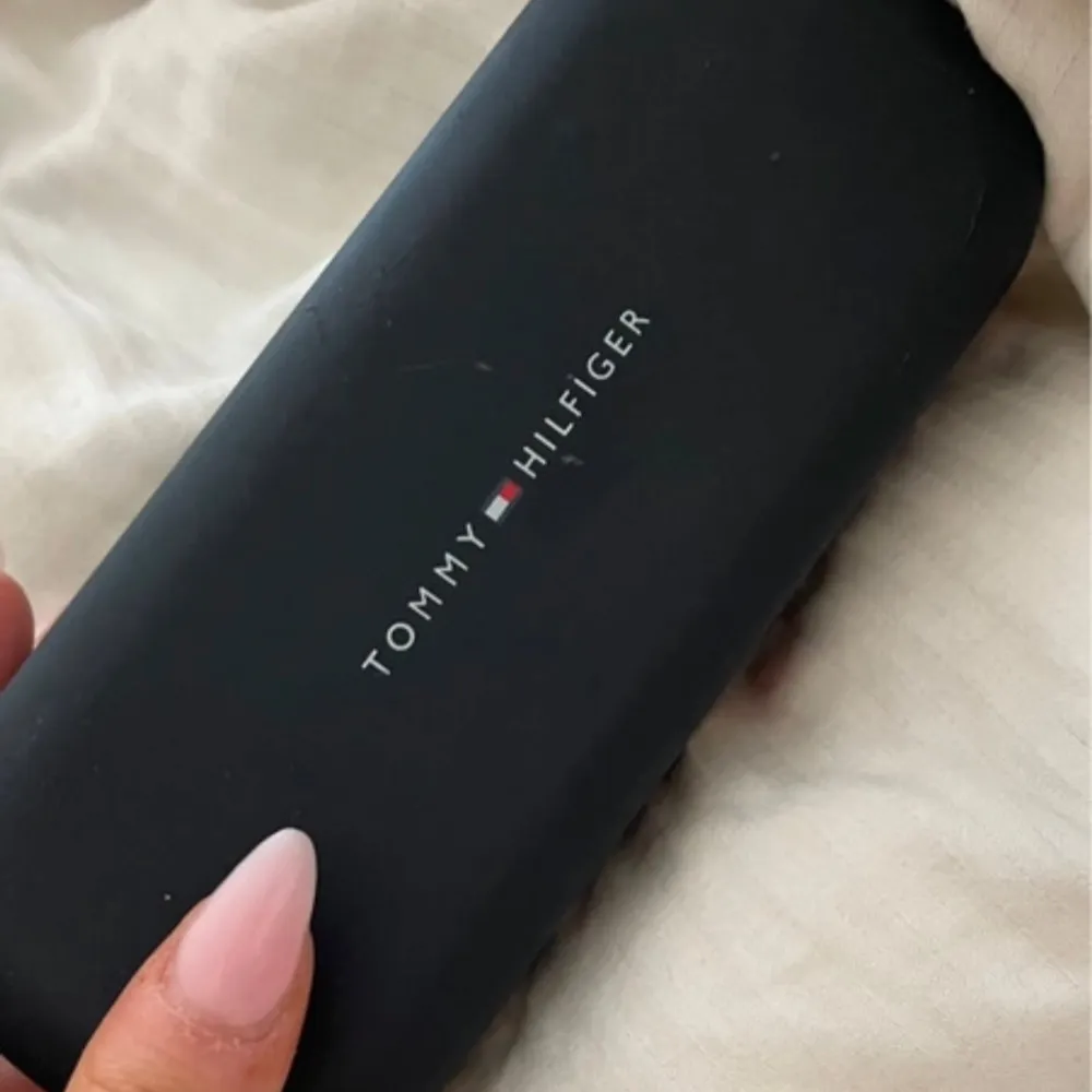 Snygga svarta solglasögon från Tommy Hilfiger med en klassisk design. De har en elegant svart båge och kommer i ett stilrent fodral med märkets logga. Perfekta för att ge en touch av stil till din outfit.. Asusteet.