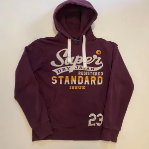 Superdry hoodie - Vinröd Superdry hoodie med tryck, Storlek M Mycket bra skick endast en liten skada längst ut på  ärmen som ni ser på sista bilden Pris kan diskuteras Skriv vid minsta fråga eller fundering💯🤝