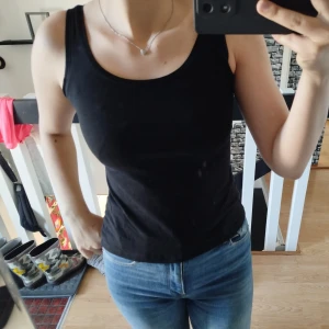 Svart linnetopp - Säljer en stilren svart linnetopp med rund halsringning. Perfekt för varma dagar eller som lager under en tröja. Toppen har en tight passform och är tillverkad i ett mjukt material för extra komfort.