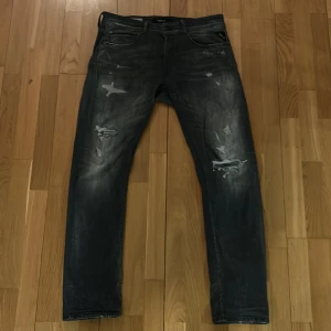 Svarta jeansbyxor från Replay - Snygga svarta jeansbyxor från Replay, modell Grover. De har en straight fit och är tillverkade i slitstarkt denim. Byxorna har en cool slitningseffekt och klassiska femficksdesign. Perfekta för en avslappnad stil. ganska bra skick ändå skulle jag säga 