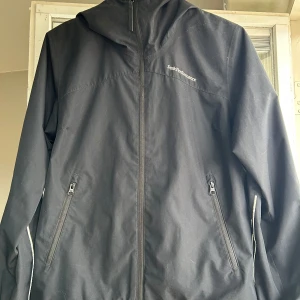 Vind och regnjacka peak performance  - Säljer en stilren svart vind och regnjacka från Peak Performance. Jackan har dragkedja framtill och två praktiska fickor med dragkedjor. Kan behöva en impregnering.