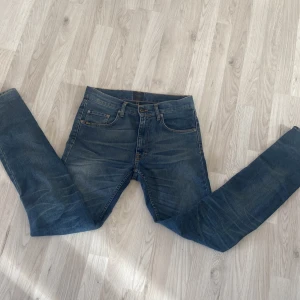 Blå jeans från Tiger of Sweden - Snygga blå jeans från Tiger of Sweden med klassisk femficksdesign. De har en normal passform och är tillverkade i slitstarkt denim. Perfekta för en stilren look.