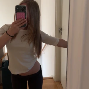 Vit kortärmad topp från Into The Classics - Säljer en stilren vit beige topp från Into The Classics. Den är kortärmad och har en klassisk rund halsringning. Perfekt för en enkel och snygg look. Den har lite längre armar än en vanlig t shirt! 🤗