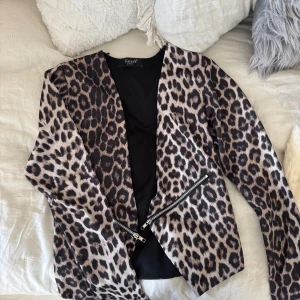 Leopardmönstrad tröja från Sisters Point - Snygg leopardmönstrad kofta från Sisters Point med dragkedjedetaljer. Perfekt för att ge din outfit en trendig touch. Koftan har en figurnära passform och långa ärmar.