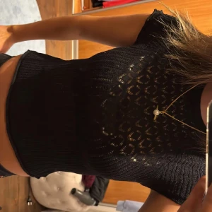 Svart ribbad topp - Snygg svart ribbad topp med korta ärmar och ett genombrutet mönster. Perfekt för en stilren look.