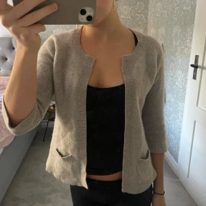 Grå kofta med trekvartsärm - Säljer en superfin grå kofta med trekvartsärm. Perfekt för både vår och höst! Den är i ett mjukt material och har två små fickor fram. 100% Kashmir! 