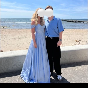 Balklänning från dressroom linné - Ljusblå balklänning med glittrigt tyg och offshoulder-design. Klänningen har en slits och har sytts upp för att ha kvar ett litet släp även med klackar  på mig som är 170, endast använd en gång och har kemtvättats efteråt