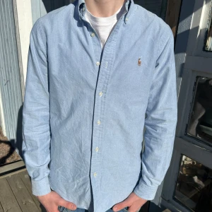 Ljusblå skjorta från Ralph Lauren - Säljer en stilren ljusblå skjorta från Ralph Lauren. Skjortan har långa ärmar och klassiska knappar framtill. Perfekt för en avslappnad men ändå uppklädd look. 🕺