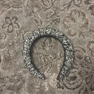 Svart och vit diadem - Snyggt diadem i svart och vitt med ett flätat mönster. Perfekt för att ge en stilfull touch till din outfit. Diademet har en texturerad yta som ger det en unik look.