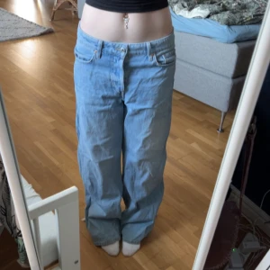 Baggy jeans i ljusblå denim - Säljer ett par ljusblå baggy jeans från H&M. De har en loose fit. Perfekta för en avslappnad stil. Ytterben - 102 cm Innerben - 78 cm Midja - 37,5 cm