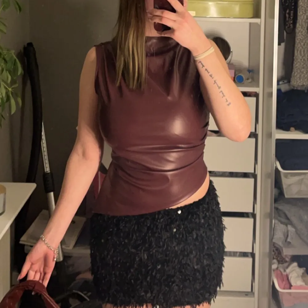 Snygg vinröd ärmlös topp i skinnimitation. Perfekt för en kväll ute. Toppen har en figurnära passform och en stilren design.. Yläosat.