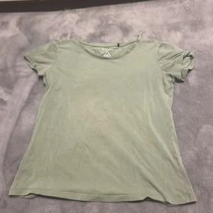 Grön t-shirt från Divided - Säljer en enkel och stilren grön t-shirt från Divided. Den har en rund halsringning och korta ärmar, perfekt för en avslappnad look. Passar bra till jeans eller shorts. Hör av dig vid intresse!