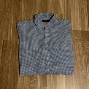 Rutig skjorta från Polo Ralph Lauren - Snygg rutig skjorta från Polo Ralph Lauren i blått och vitt. Skjortan har klassisk krage och knappar framtill. Perfekt för en stilren look. Kolla gärna in resten av butiken, möjlighet på bundle finns.