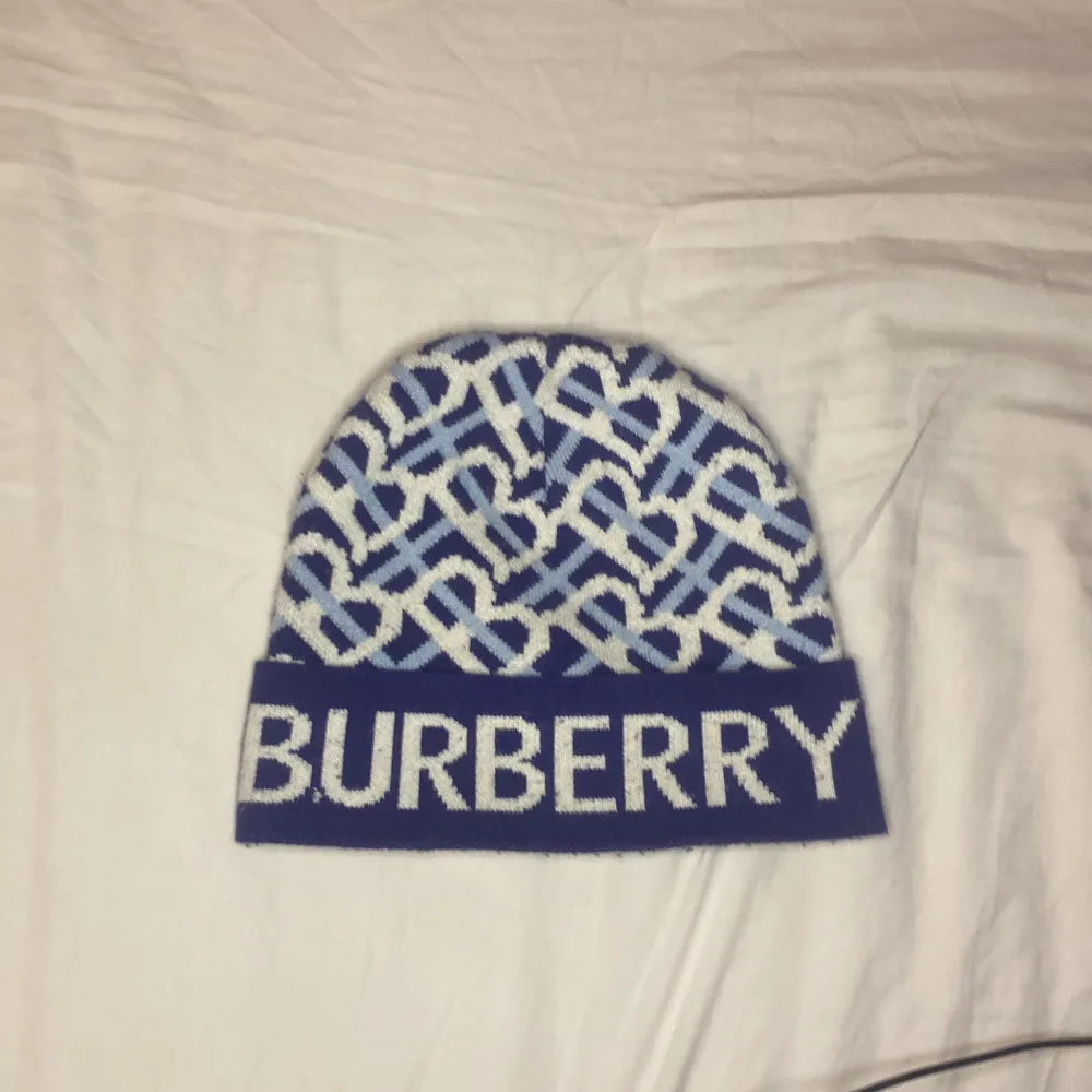 Snygg blå och vit mössa från Burberry med ett unikt mönster och logotyp framtill. Perfekt för att hålla stilen i kallare väder.. Asusteet.
