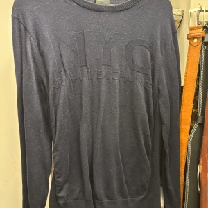 Mörkblå tröja från Armani Exchange - Säljer en stilren mörkblå tröja från Armani Exchange med texten 'NYC' diskret präglad på framsidan. Tröjan har långa ärmar och en rund halsringning. Perfekt för en avslappnad men ändå snygg look.