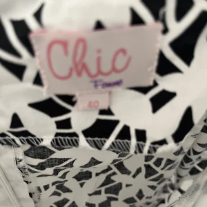 Svartvit mönstrad klänning från Chic - Snygg svartvit klänning från Chic med ett abstrakt mönster. Klänningen har smala axelband och en figurnära passform. Perfekt för en stilren look.