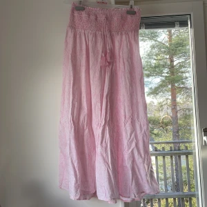 Rosa långkjol från Gina Tricot - Säljer en söt rosa långkjol från Gina Tricot. Kjolen har en smockad midja och är gjord i ett lätt och luftigt material. Perfekt för varma dagar! 💖Är aldrig använd men har någon defekt (exempel visas på bild 4, lösa trådar)