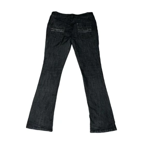 Gråa Lågmidjade Jeans  - Svarta/mörkgrå lågmidjade bootcut jeans med bling på både framsida & baksida! Bra skick för att vara secondhand. Midjemått tvärs över: 37cm & Innerbenslängd: 79cm