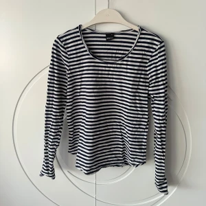 Randig långärmad topp från Gina Tricot - Säljer en stilren randig topp från Gina Tricot i storlek S. Den har ett klassiskt marinblå mönster och långa ärmar, perfekt för en avslappnad look. Bra basic plagg i garderoben✨