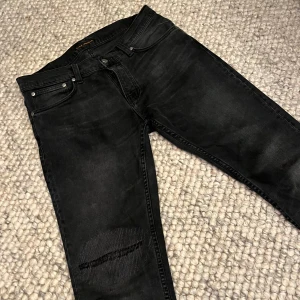 Nudie jeans svarta - Tja tja! Jag säljer dessa fetta svarta nudie jeans i modellen grim trim i storlek 33/32. Dom är i bra skick men dom har blivit sydda vid knäet, det syns dock knappt när man har på dem i dagsljus! Tveka inte på att ställa frågor vid funderingar - Mvh Edvin 